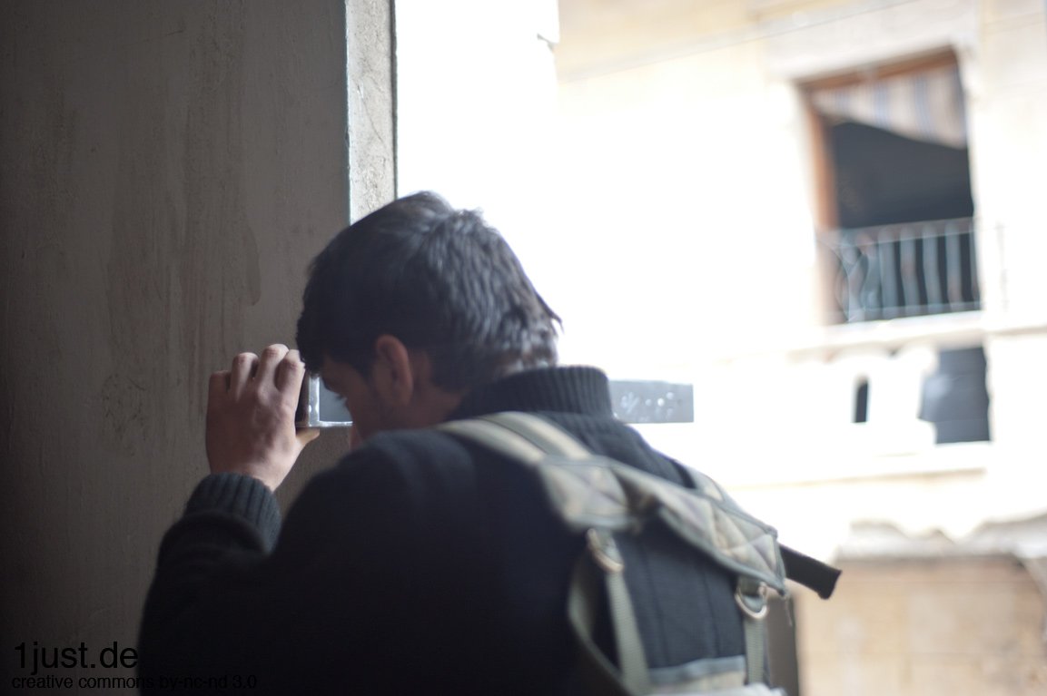 Aleppo – Fighter keeping watch through a crack in the wall